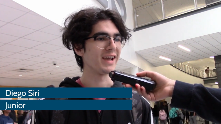 A make student with glasses speaks into a microphone.