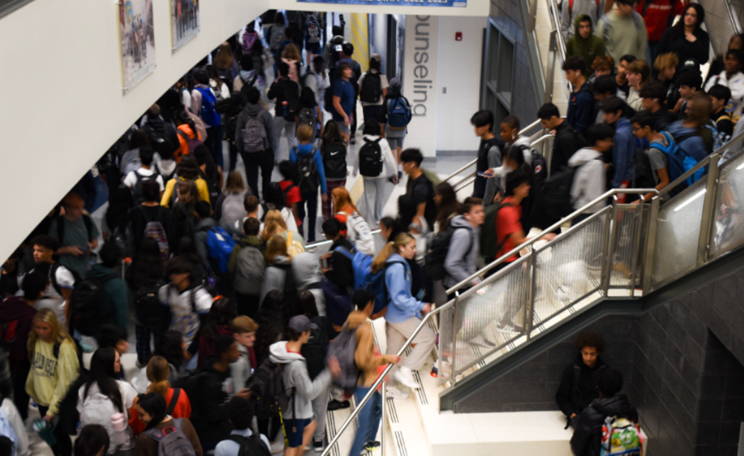 Students fill the main hallway and library staircase during a passing period.