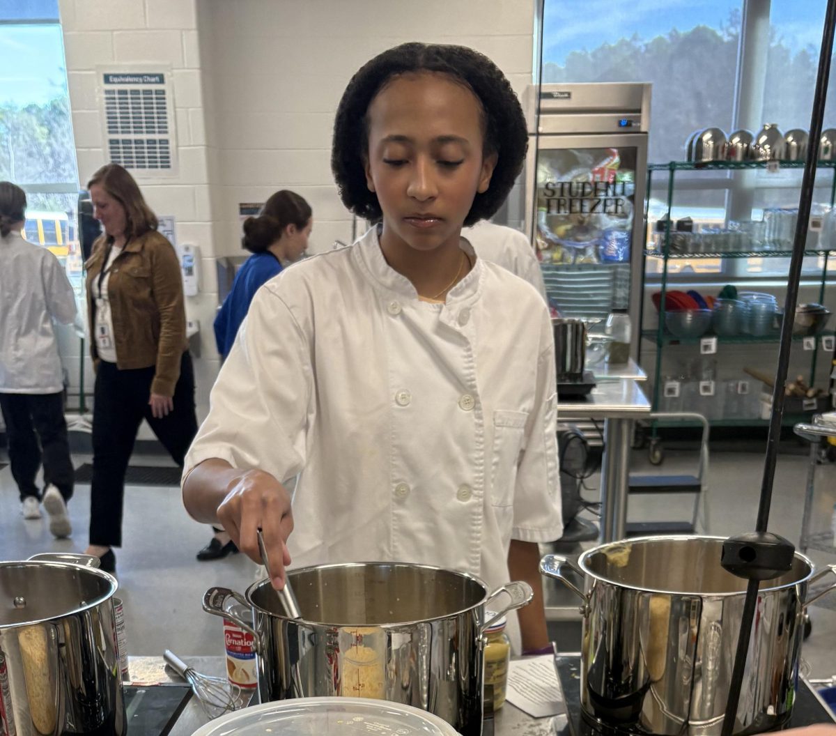 Senior Alicia Robillard makes mac and cheese to include as part of the seventy holiday meals prepared for families in need.